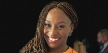 Fotografia com retrato de Chimamanda Ngozi Adichie: uma mulher sorridente com cabelos amarrados em tranças, usando brincos.
