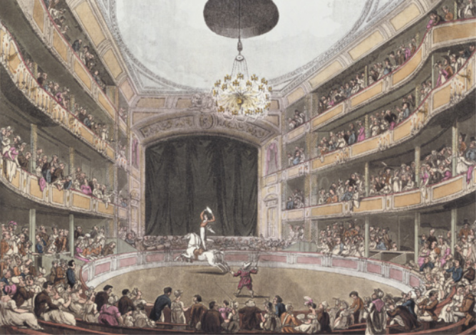 Gravura colorida representando o interior de um teatro com arena circular ao centro e três andares de arquibancadas, todos ocupados por espectadores. Na arena, um homem está em pé sobre um cavalo em movimento, enquanto outra pessoa permanece em pé no centro do espaço.