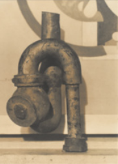 Fotografia de uma escultura feita com canos metálicos enrolados, com encaixes e peças que se acoplam.