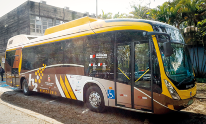 Fotografia de um ônibus de transporte coletivo com a indicação H 2 na lateral. Ele está em uma rua com um edifício ao fundo.