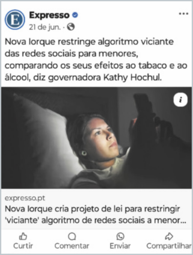 Publicação do post de uma rede social. O post é do jornal Expresso, publicado no dia 21 de junho. Há o texto: 'Nova Iorque restringe algorítimo viciante das redes sociais para menores, comparando os seus efeitos ao tabaco e ao álcool, diz governadora Kathy Hochul.' Logo abaixo do texto, há a foto de uma jovem deitada no escuro mexendo no celular, a luz do aparelho reflete em seu rosto. Há também, botões de curtir, comentar, enviar e compartilhar.