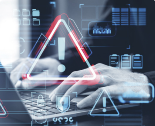 Imagem de mãos digitando em um teclado de computador com diversos ícones digitais sobrepostos, incluindo símbolos de alerta triangulares com ponto de exclamação no centro, cadeados, gráficos e ícones de energia, todos em tons de azul e vermelho, sugerindo um ambiente virtual de monitoramento ou detecção de riscos e segurança digital.
