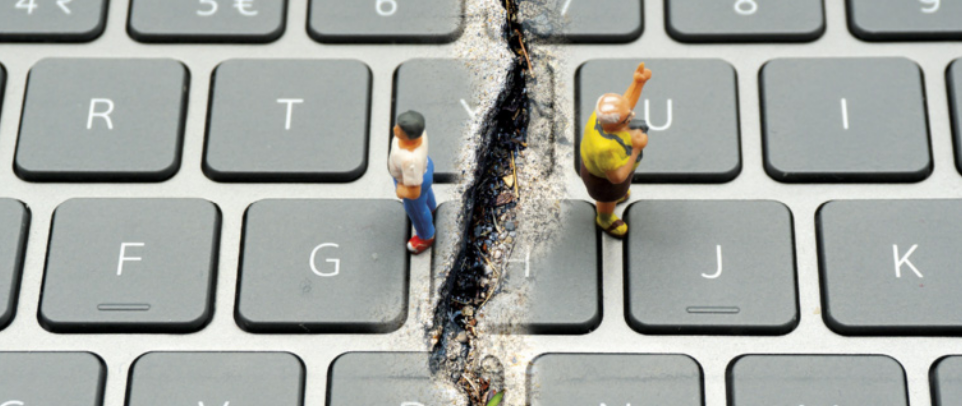 Imagem de um teclado de computador cinza com uma grande rachadura irregular no centro, separando duas pequenas figuras humanas posicionadas sobre as teclas: uma figura à esquerda com camiseta branca e calça azul, e outra à direita com camiseta amarela e braço erguido em sinal de protesto ou comemoração, criando um contraste visual entre os dois lados divididos.