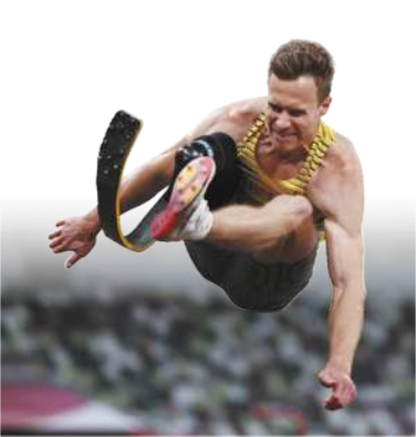 Fotografia de Markus Rehm. Ele é um paratleta, e está realizando um salto em distância, com as pernas estendidas à frente do corpo, sentado no ar, com uma prótese em uma das pernas.