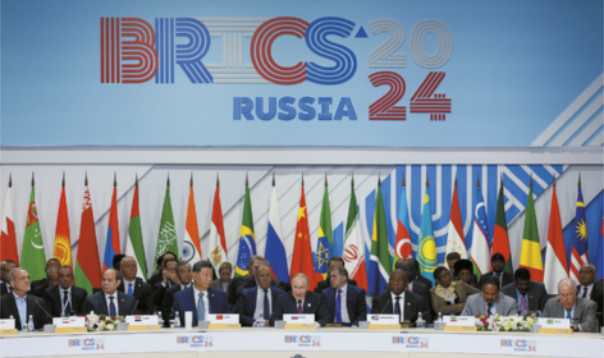 Imagem de autoridades mundiais reunidas em um evento. Elas estão sentadas e, atrás delas, há bandeiras de diversos países hasteadas.