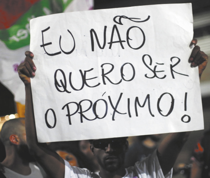 Imagem de manifestante negro segurando um cartaz, que contém a seguinte frase: Eu não quero ser o próximo!