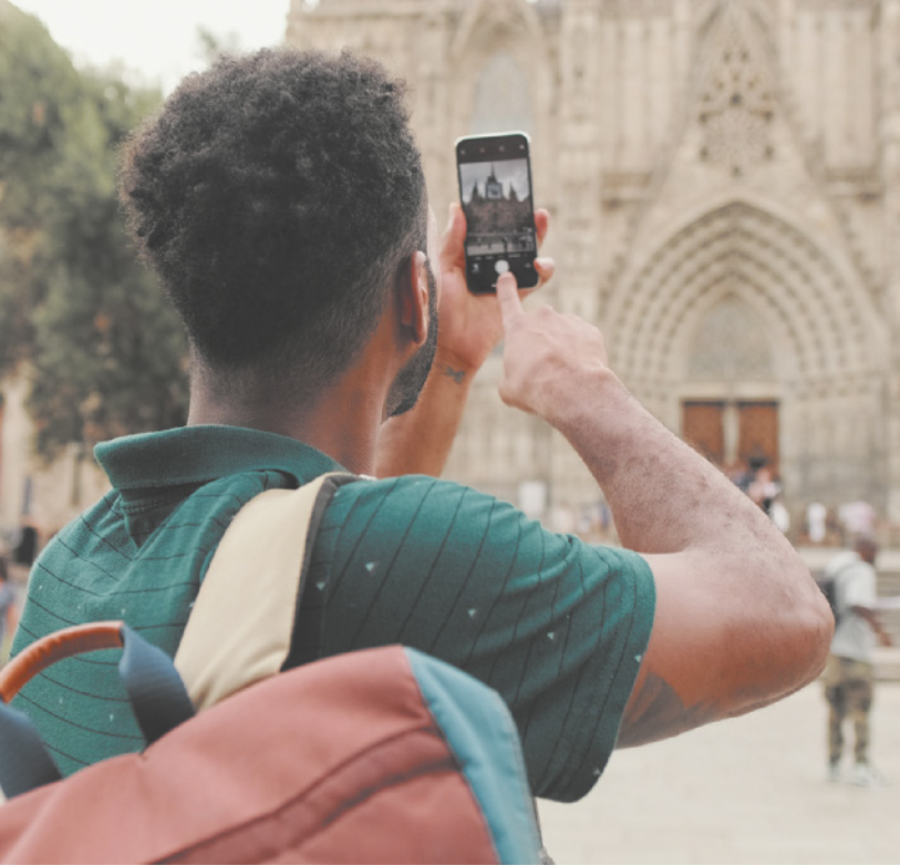 Imagem de homem utilizando um celular para fotografar a fachada de uma igreja.