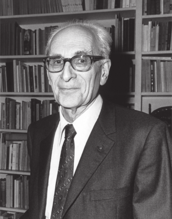 Fotografia em preto e branco de Claude Lévi-Strauss. Ele é idoso, calvo e usa óculos, terno e gravata. Atrás dele, há estantes com livros.