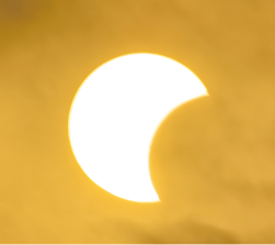 Fotografia do Sol, em formato de uma circunferência brilhante com uma parte arredondada encoberta pela Lua em um eclipse solar.