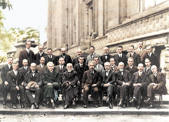 Fotografia de muito homens organizados em três fileiras, na qual os da frente estão sentados e os de trás estão em pé. Eles usam roupas incluindo terno e gravata ou casaco e alguns seguram chapéus.