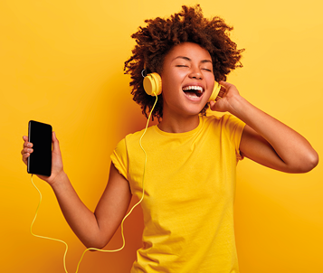 Fotografia de uma mulher usando camiseta amarela, segurando um smartphone conectado a um fone amarelo em seu ouvido. Ela está de olhos fechados e sorrindo.