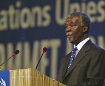 Foto de Thabo Mbeki. Ele é um homem negro, possui bigode, barba e está discursando.