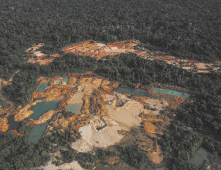 Foto aérea de extensa área descampada, com muita lama e acúmulo de água.
