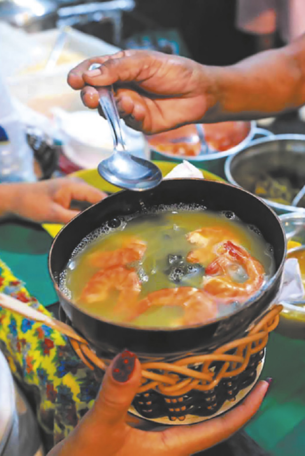 Foto de tacacá, em uma tigela. O tacacá é um caldo amarelo, com folhas e camarões em seu interior.