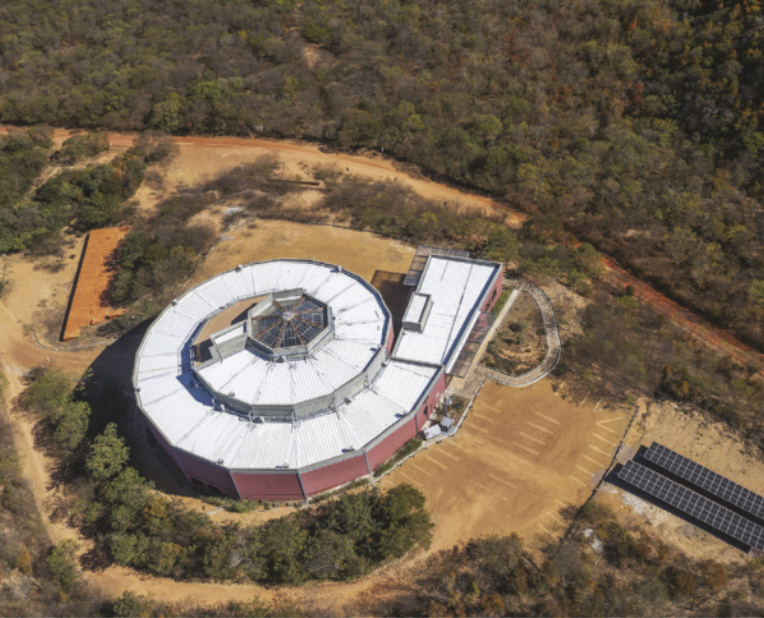 Foto aérea de museu que possui o formato de uma espiral. Ao lado, estão instalados painéis solares.