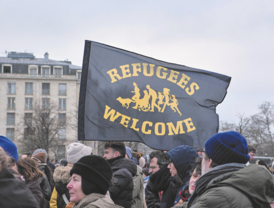 Foto de pessoas em manifestação. Elas seguram uma bandeira com inscrições em inglês.