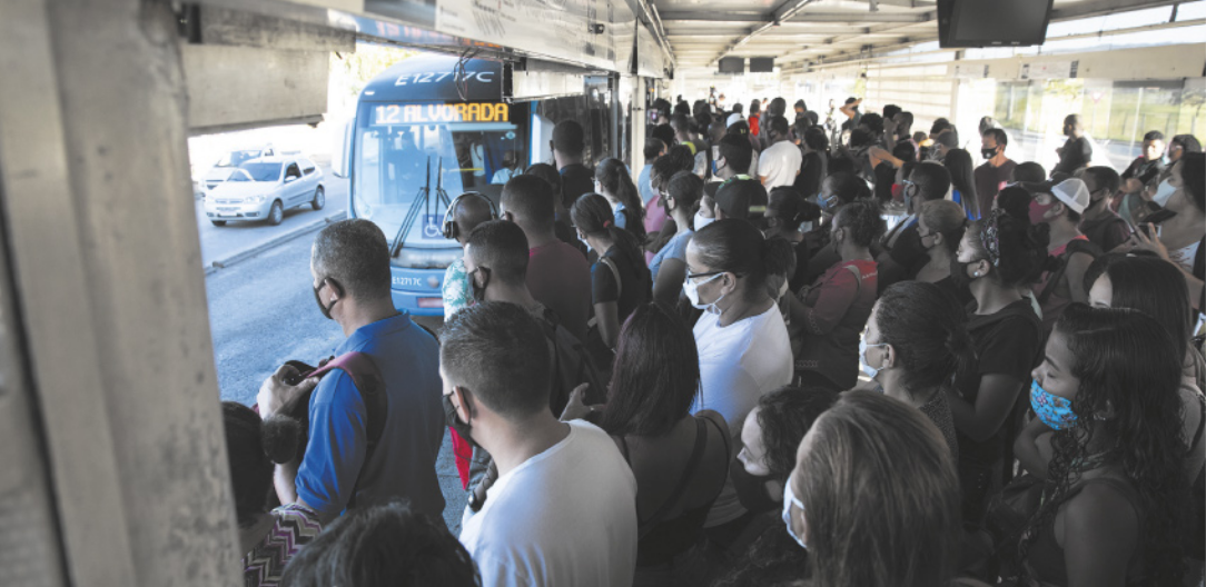 Foto de muitas pessoas reunidas no ponto de ônibus.
