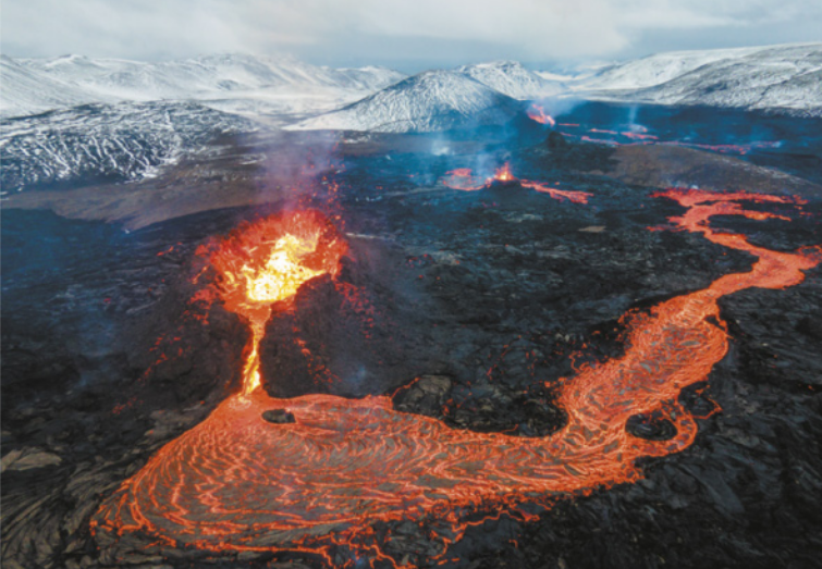 Foto de vulcão em erupção. Muita lava é expelida pela cratera, espalha-se pela superfície no vulcão e chega às localidades mais baixas.