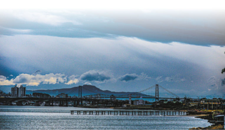 Foto de cidade litorânea, onde há uma grande ponte. Essa ponte conecta uma ilha ao continente.