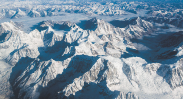 Foto de uma grande cadeia de montanhas, com muita neve na parte superior.