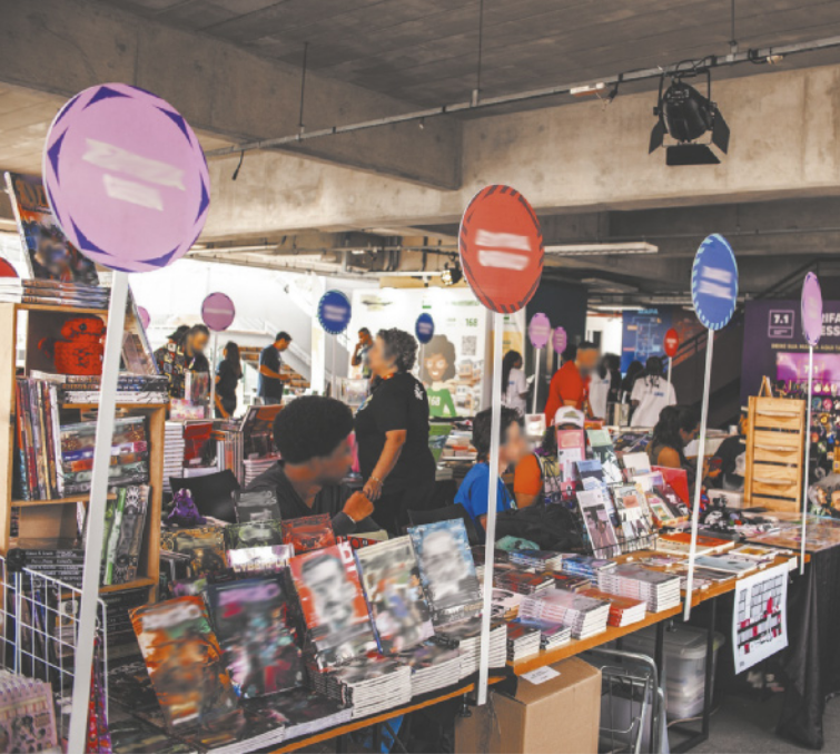 Foto de pessoas expondo livros e quadrinhos para venda.