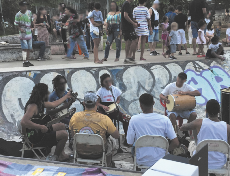 Foto de pessoas tocando instrumentos e cantando. Elas estão sentadas em círculo.
