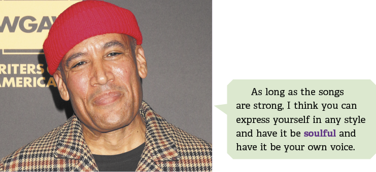 Fotografia de busto de um homem usando gorro vermelho e uma jaqueta xadrez. Ele sorri de lábios fechados, e ao lado há um balão de fala escrito em inglês: As long as the songs are strong, I think you can express yourself in any style and have it be soulful and have it be your own voice. A palavra soulful está destacada.