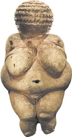 Fotografia de uma estatueta representando o corpo de uma mulher. Ela tem a cabeça representada com relevos, sem o rosto evidente, os seios são grandes e o quadril é largo.