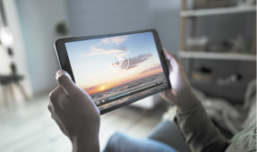 Fotografia de uma pessoa segurando um tablet com um vídeo sendo exibido.