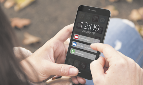 Fotografia de uma pessoa segurando e manuseando um smartphone com itens de notificação sendo exibidos na tela.