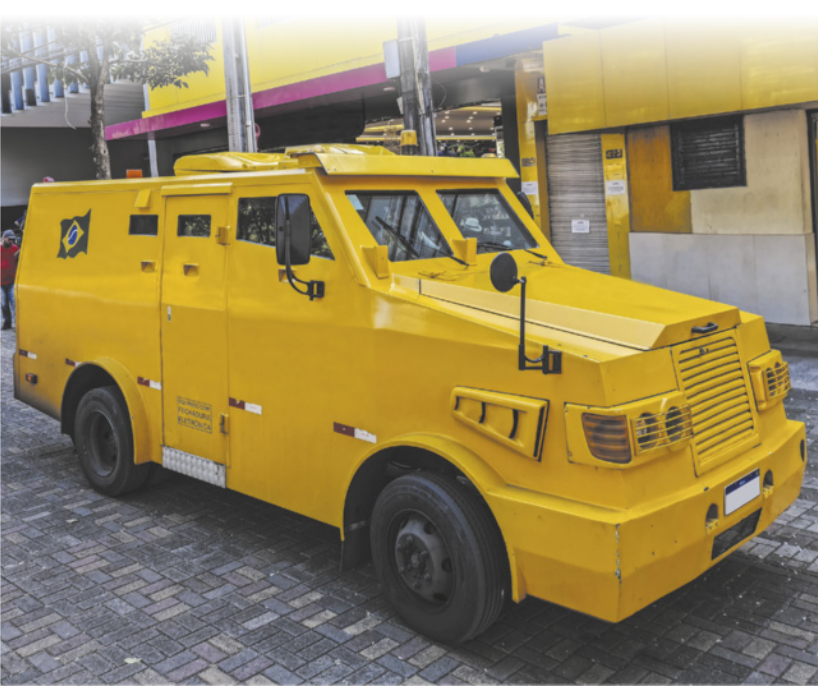 Fotografia de um carro alto e robusto, com formato retangular. Ele possui janelas e para-brisa pequenos.