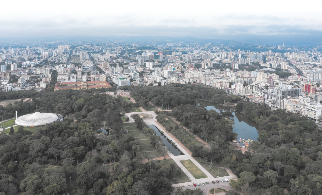 Fotografia com vista de cima de área urbana. Há um grande parque bastante arborizado em meio aos prédios.