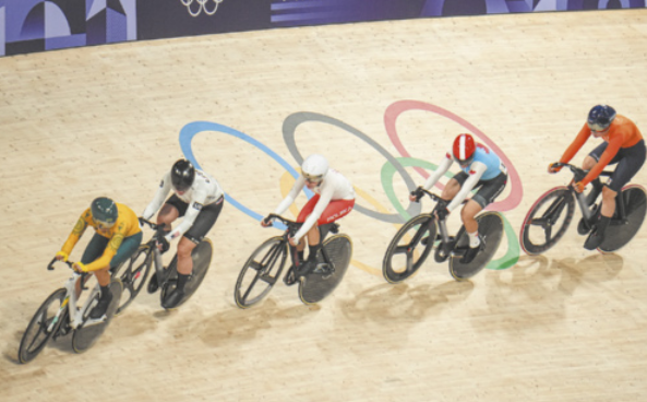 Fotografia de atletas pedalando em pista de ciclismo.