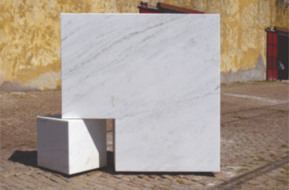 Fotografia de um cubo de mármore branco. Do canto inferior direito foi deslocado um pequeno pedaço cúbico.