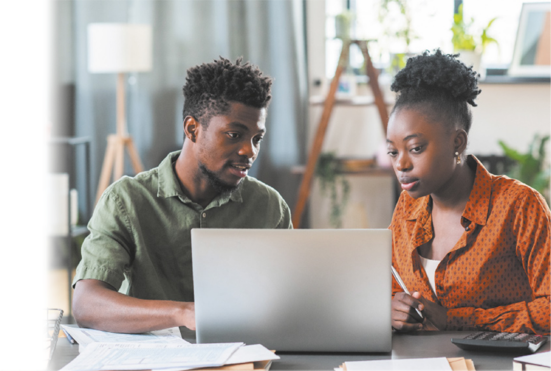 Fotografia de um homem e uma mulher conversando em frente a um notebook.