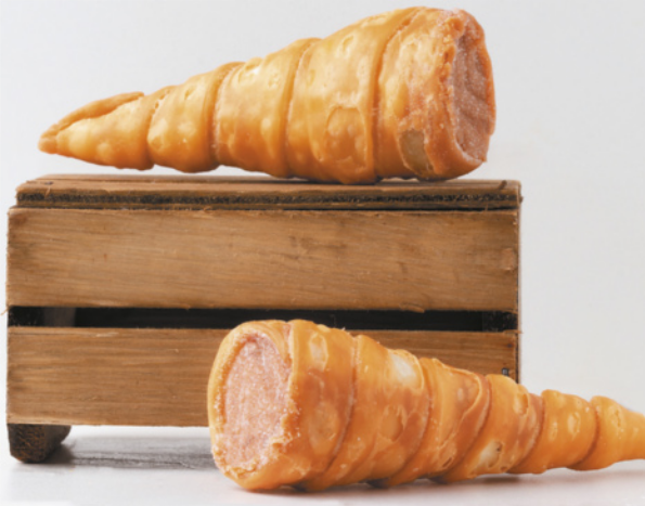 Fotografia de dois doces em formato cônico. Eles possuem uma casca de cor caramelo e formato cônico, aberta na base, onde é possível ver um creme como recheio.
