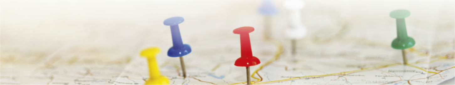 Fotografia de um mapa com alguns alfinetes coloridos espetados.