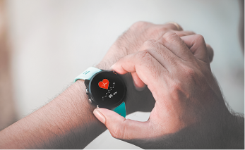 Fotografia de uma pessoa ajustando um smartwatch em seu pulso. O smartwatch tem uma tela preta que exibe um ícone de coração vermelho com batimentos cardíacos e informações abaixo dele.