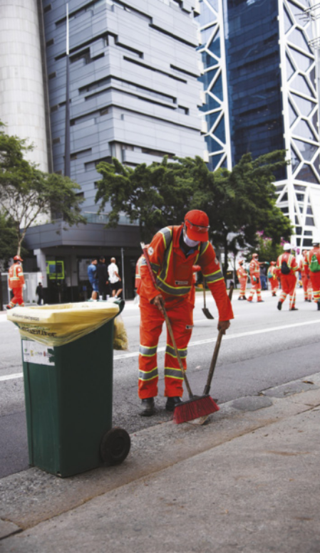 Imagem de garis varrendo uma avenida.