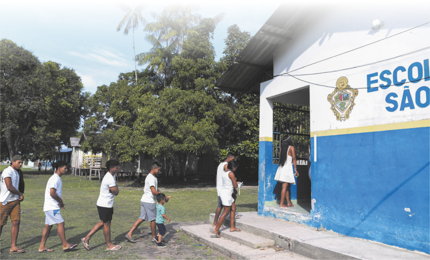 Imagem de pessoas enfileiradas entrando em uma escola.