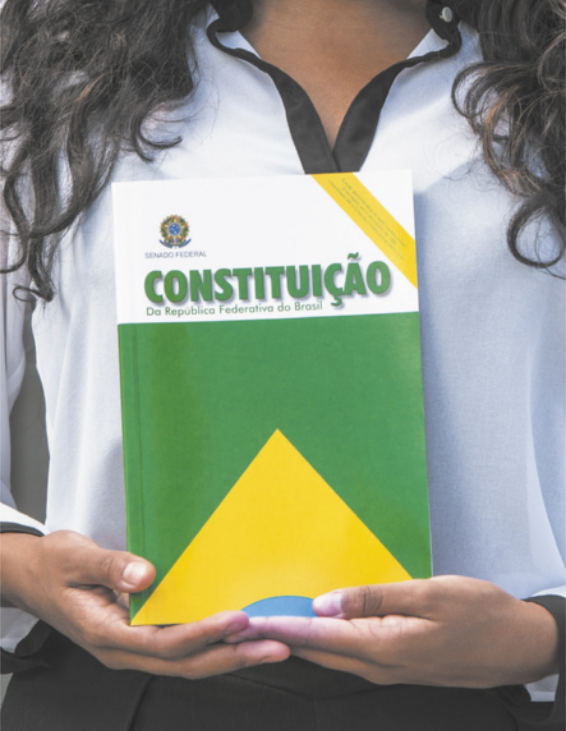 Imagem de mulher segurando a Constituição da República Federativa do Brasil.