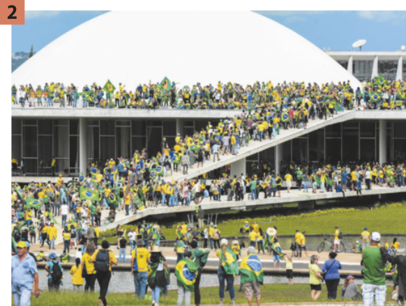 2. Imagem de pessoas invadindo o edifício do Congresso Nacional. Elas usam camisas com as cores da bandeira do Brasil e carregam a própria bandeira nas costas.