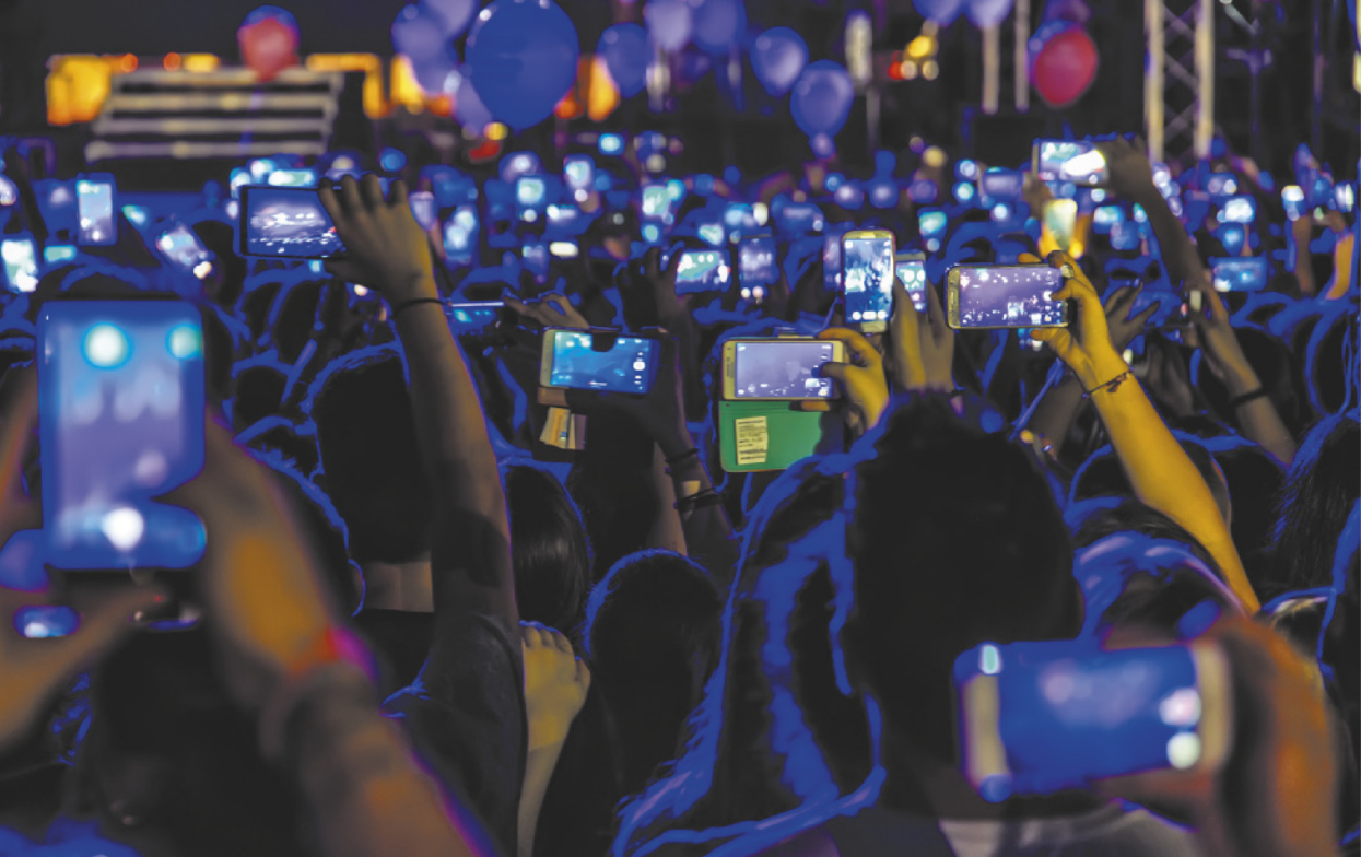 Imagem de pessoas registrando um evento cultural por meio de celulares.
