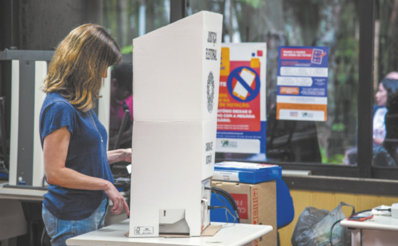 Imagem de eleitora em uma cabine de votação.