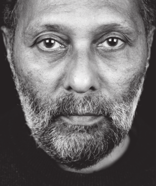Fotografia em preto e branco de Stuart Hall. Ele possui barba grisalha e está com expressão séria.