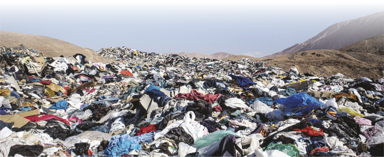 Imagem de pilhas de roupas espalhadas ao longo de uma paisagem desértica.