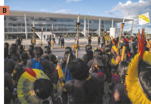 B. imagem de manifestantes indígenas. Eles estão com o corpo pintado e alguns deles usam cocar e carregam lança.