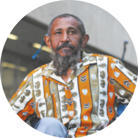 Fotografia de Nêgo Bispo. Ele é negro, idoso, possui barba longa grisalha e usa camisa estampada.