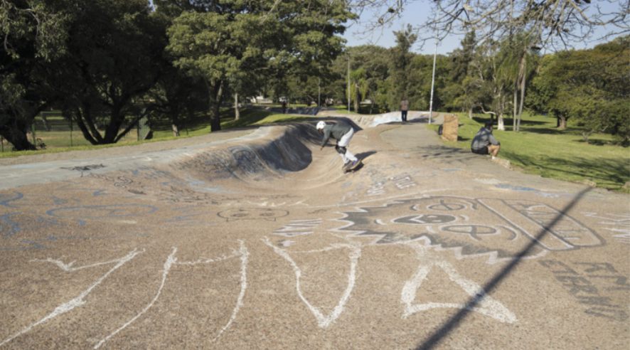 Imagem de pessoa andando de skate. Ela está em uma pista com a parte central mais funda que as bordas.