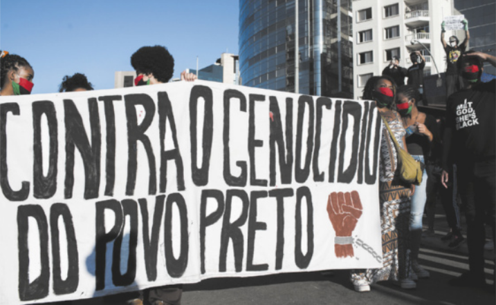 Imagem de manifestantes segurando uma faixa com a seguinte frase: contra o genocídio do povo preto.